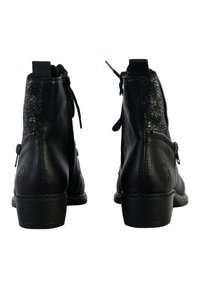 Une paire de bottines en cuir noir à lanières latérales et talons texturés, vues de l'arrière sur un fond blanc.