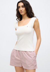 Biały top z kwadratowym dekoltem, krótkimi rękawami i fakturowaną tkaniną; zestawiony z czerwono-białymi szortami w paski z detalem w postaci guzika.