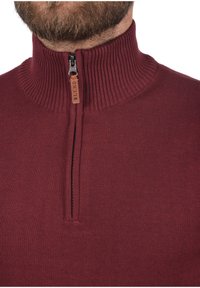 Bordo pulover s rajsferšlusom napravljen od pletene tkanine. Ima rebrasti ovratnik i rajsferšlus s kožnom oznakom označenom "BLEND."