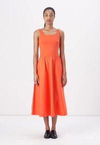 Orange sleeveless dress with a fitted bodice and flowing midi skirt. Made of soft fabric, it features a simple, classic design.