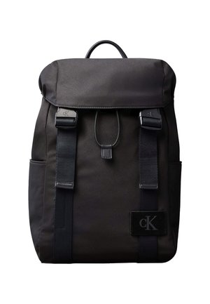 Black Calvin Klein backpack with flap closure, two front straps with buckles, side pockets, and a top handle.