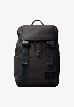 Melna Calvin Klein mugursoma ar pārsegu aizdari, divām priekšējām siksnām ar sprādzēm, sānu kabatām un augšējo rokturi.