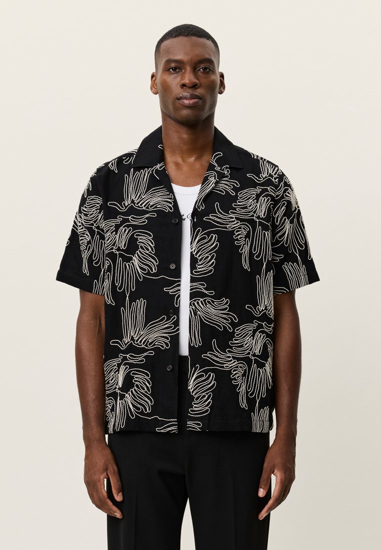 Chemise noire à manches courtes avec motifs abstraits de mains blanches, boutonnée à l'avant, coupe décontractée, fabriquée en tissu léger.