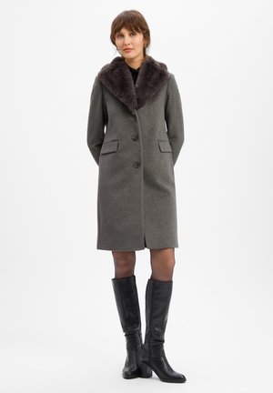 Grauer Wollmantel mit einem plüschigen, dunklen Pelzkragen, zwei vorderen Taschen, Knopfverschluss und geradem Schnitt. Ein Paar schwarze kniehohe Stiefel.