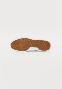 Rubber sole with a textured brown surface, round grips, and a white edge. Includes "GOODYEAR" logo in gold.