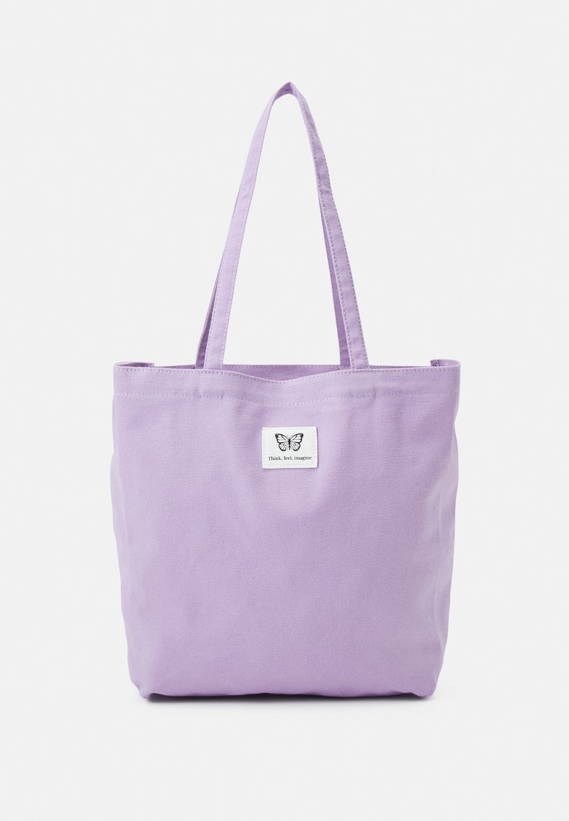 Sac fourre-tout en toile lavande avec deux bretelles d'épaule et une petite étiquette blanche affichant un papillon et le texte "Penser, ressentir, imaginer."