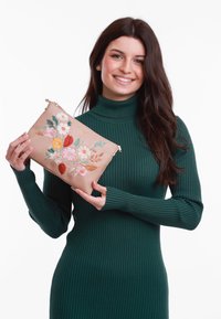 Beige Leder-Clutch mit floralem Stickerei in Pink, Rot und Grün. Rechteckige Form mit einem Reißverschluss oben. Modell hält sie vor einem weißen Hintergrund.
