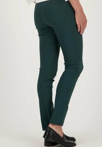 Slim-fit groene broek gemaakt van rekbaar materiaal, met achterzakken en een geborduurd logo. Draag ze met zwarte leren instappers, afgewerkt bij de enkels.