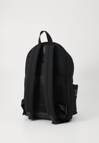 Sac à dos noir avec un dos en mesh, des bretelles rembourrées, une poignée supérieure et une poche latérale zippée pour le rangement.