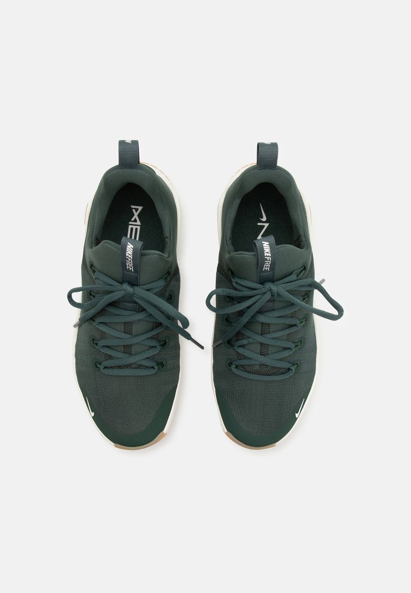 Ciemnozielone buty sportowe z siateczkowej cholewki, teksturowanymi sznurowadłami, wyściełanym kołnierzem oraz białą podeszwą z małym logotypem Nike po boku.