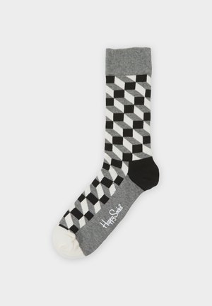 Chaussette en tricot grise avec un motif géométrique de diamants noir et blanc, avec un talon noir, un bout gris et un capuchon blanc ; logo de la marque imprimé sur le côté.