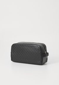 Black cosmetic bag featuring a textured pattern, rectangular shape, zipper closure, and a side handle for easy carrying.