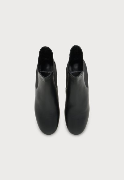 Paire de bottines noires en cuir à enfiler avec bouts arrondis et panneaux latéraux élastiques, vues de dessus sur un fond uni.