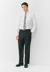 Biała koszula z długimi rękawami, czarne spodnie i muchę w wzór z odcieniami szarości, burgundowymi i złotymi akcentami. Czarne buty i pasek.