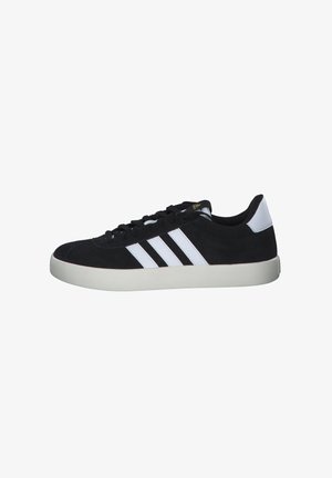 Zapatillas de ante negro con diseño de tres rayas blancas, punta redonda, cordones negros y suela de goma blanca. Estilo minimalista con textura suave.