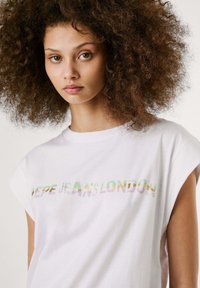 Valge puuvillane T-särk lühikeste rullitud varrukatega, mille rinnal on mitmevärviline "PEPE JEANS LONDON" logo. Sile tekstuur.