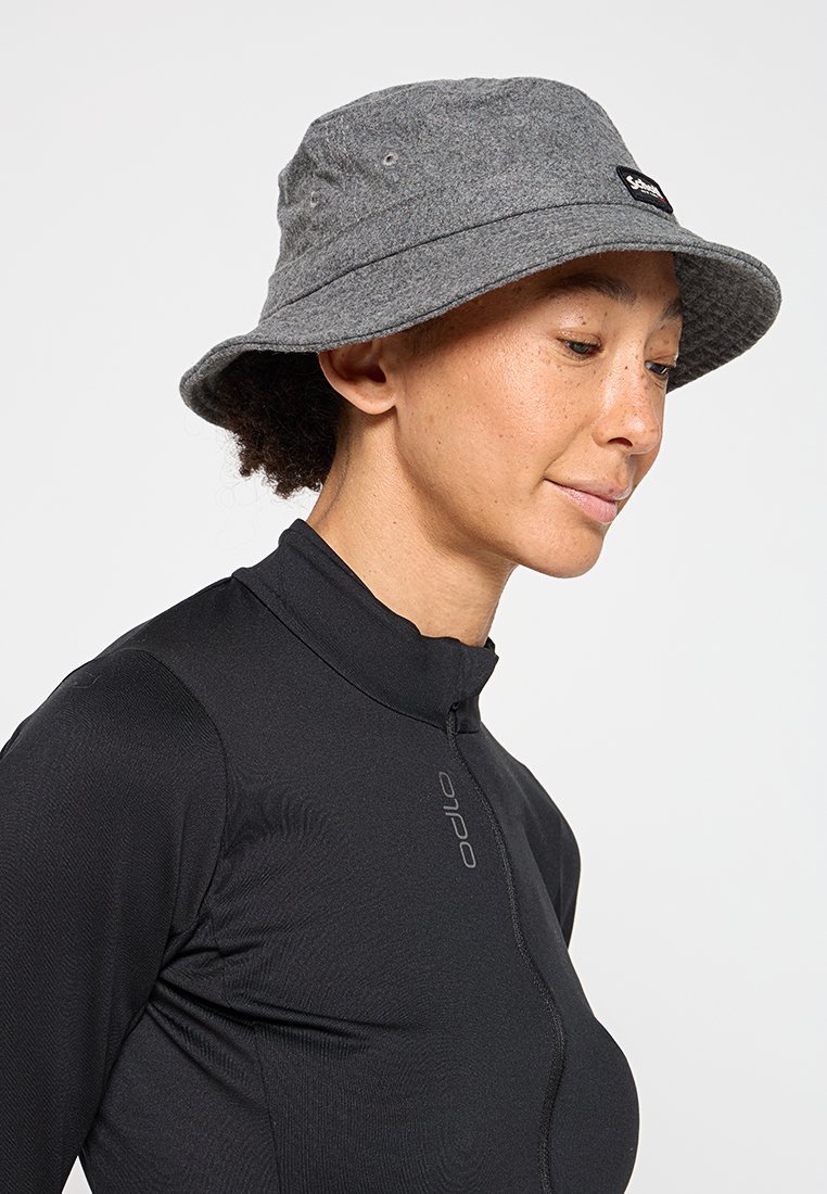Cappello a secchi grigio con una larga tesa, dotato di aree di ventilazione e un patch logo nero; indossato con una maglia zip-up nera da atletica.