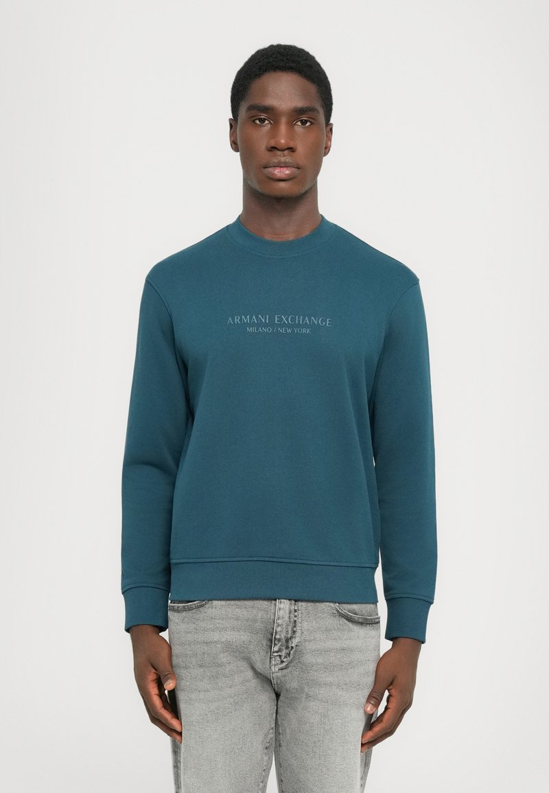 Tyrkisk bomullssweatshirt med rund hals, ribbede mansjetter og hem. Har fronttekst "ARMANI EXCHANGE MILANO/NEW YORK" i kontrastfarge.