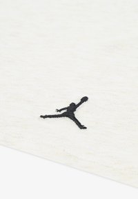 Tissu en coton blanc avec une finition texturée présentant un logo Jumpman noir brodé en pose aérienne.