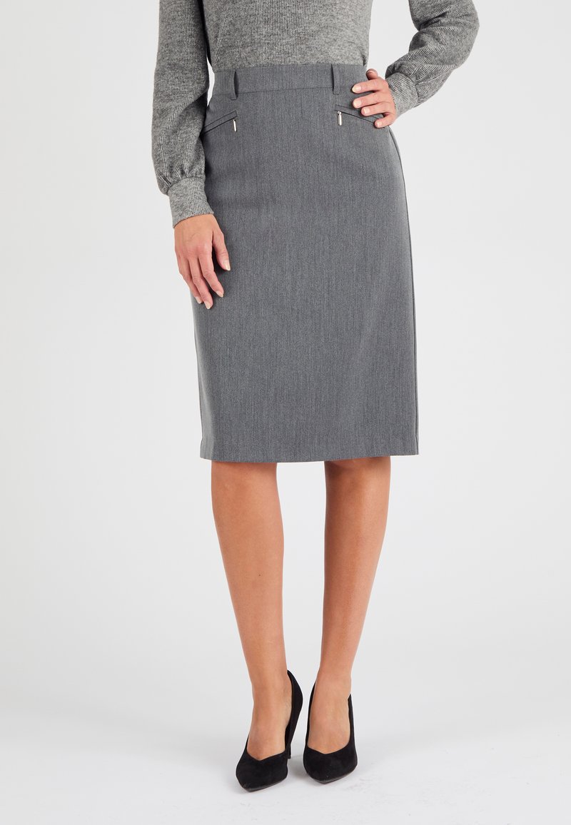 Jupe crayon grise en tissu texturé, dotée de poches avant avec des accessoires en argent. Complétée par des chaussures à talons hauts noires.