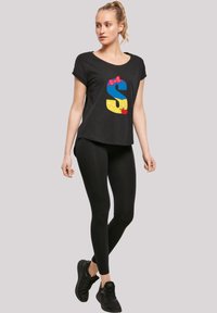 Black t-shirt with short sleeves, featuring a colorful graphic design on the front, paired with black leggings and black athletic shoes.