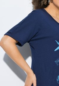 Námorně modré tričko s krátkým rukávem, měkká textura, s lehce modrým mořským motivem na přední straně.