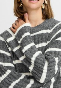 Grau und weiß gestreifter Pullover mit gerippter Textur. Verfügt über weite Ärmel und einen Rundhalsausschnitt, der ein weiches, gemütliches Material zeigt.