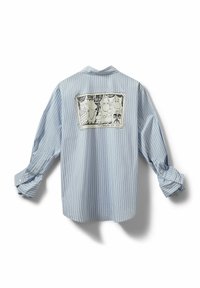 Zils un balts svītrains krekls ar brīvu piegriezumu, mugurpusē ar karikatūras attēlu. Garas piedurknes uzlocītas pie aprocēm.