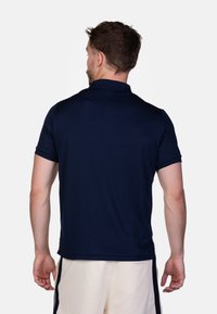 Marineblauwe polo met een kraagontwerp, korte mouwen en een gladde textuur. Heeft een rechte zoom en minimale stikdetails.
