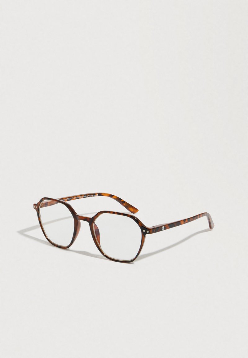 Kilpikonnakuviolliset silmälasit, joissa on geometrinen kahdeksankulmainen kehys. Kirkkaat linssit, ohuet raajat, joissa hienovaraiset kuviot, ja metalliset yksityiskohdat saranan läheisyydessä.