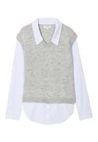 Maglione grigio lavorato a maglia senza maniche con scollo a V indossato sopra una camicia a maniche lunghe a righe blu chiaro. Dettagli evidenti nella costa dell'orlo e del colletto.