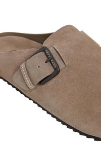 Mockasiner i suède i ljusbrun med en svart metallspänne och kontrasterande sömmar. Texturerad innersula och gummiyttersula.