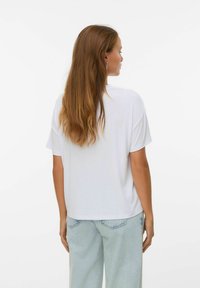 Vit, kortärmad T-shirt med avslappnad passform, i kombination med ljusblå jeans. Mjuk tygkvalitet, enkel design och inga synliga logotyper.