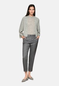 Gray knit cardigan over a light gray sweater, paired with gray striped trousers and light gray flats with a decorative buckle detail.