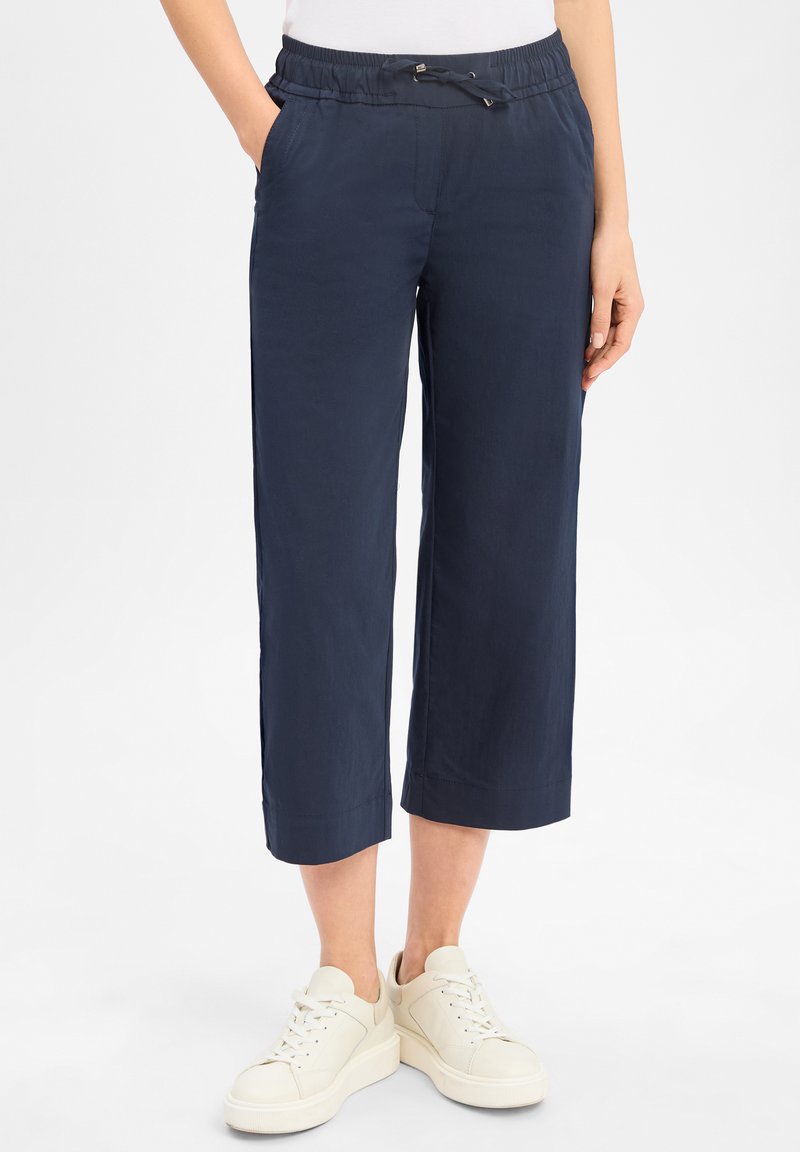 Marineblauwe cropped broeken met een elastische tailleband en een trekkoord. Voorzien van zijzakken en een soepele, lichte stof. Gekocht met witte sneakers.