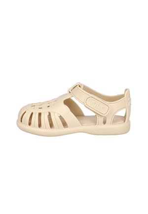 Sandalia beige para niños con puntera cerrada, múltiples tiras laterales, cierre ajustable de velcro y suela plana.