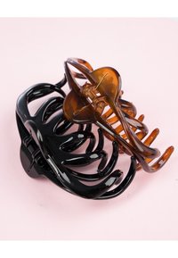 Due pettini per capelli, uno nero e uno tartarugato, entrambi realizzati in plastica lucida con design curvi e interconnessi e componenti visibili.