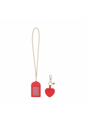 Portachiavi in pelle rossa con portacarta trasparente e un charm a forma di cuore rosso separato. Dotato di accessori in metallo color oro e una tracolla a catena.