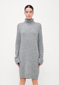 Robe à col roulé gris en tissu tricot doux, avec des manches longues à poignets prolongés et une coupe décontractée.