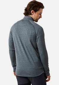 Grijze langslavende shirt met een gestructureerd patroon, hoge kraag en raglanmouwen. Bevat contrasterende stiksels en een lichtgebogen zoom.