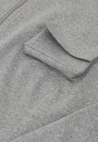 Szary hoodie na zamek, wykonany z miękkiego, teksturowanego materia łu, posiadający kieszeń na lewym rękawie oraz widoczny zamek błyskawiczny.