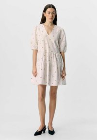 Robe rose clair avec décolleté en V, manches bouffantes et design à volants. Présente des broderies florales multicolores et une silhouette fluide.