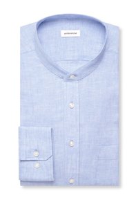 Chemise en lin bleu clair avec col mao et boutons blancs, soigneusement pliée, montrant une manchette et une poche poitrine.