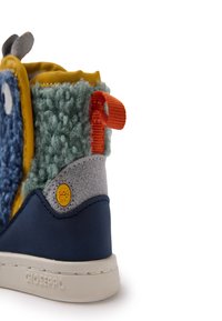 Zapatilla azul y verde con parte superior texturizada, acento naranja y forro suave. Presenta un panel de gamuza gris y logotipo de marca amarillo.