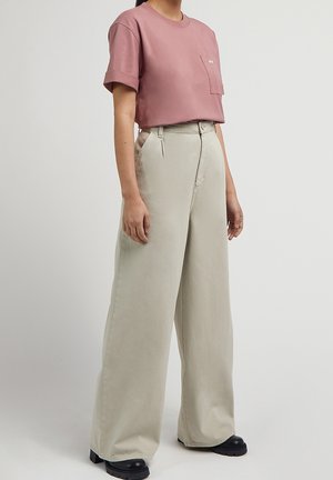 Short pink cropped t-shirt with a chest pocket, paired with light beige wide-leg trousers. Material appears soft with a smooth texture.