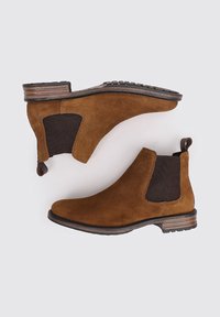 Botines de ante marrón con paneles elásticos en los lados y lengüetas para tirar, que presentan un tacón apilado y una suela de goma texturizada.
