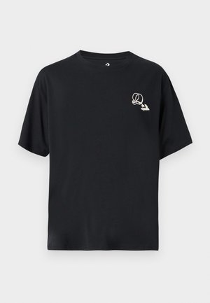 Svart bomulls-t-shirt med avslappnad passform, korta ärmar och en liten, kontrasterande grafisk logotyp på vänster bröst. Klassisk rund halsringning.