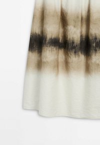 Lang hvid nederdel med et gradient tie-dye mønster, der går fra beige til mørkebrun, lavet af blødt, tekstureret stof og med en A-formet silhuet.