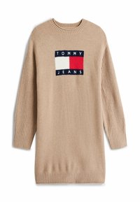 Beige Strickkleid mit langen Ärmeln und gerippten Ärmeln sowie Saum, mit einem Tommy Jeans Logo-Patch in Rot, Weiß und Marineblau.