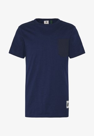Granatowy t-shirt z krótkim rękawem i okrągłym dekoltem, z kieszenią na piersi po lewej stronie oraz małą białą prostokątną metką przy krawędzi.
